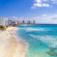 beach with buildings and clear blue water cancun travel tips