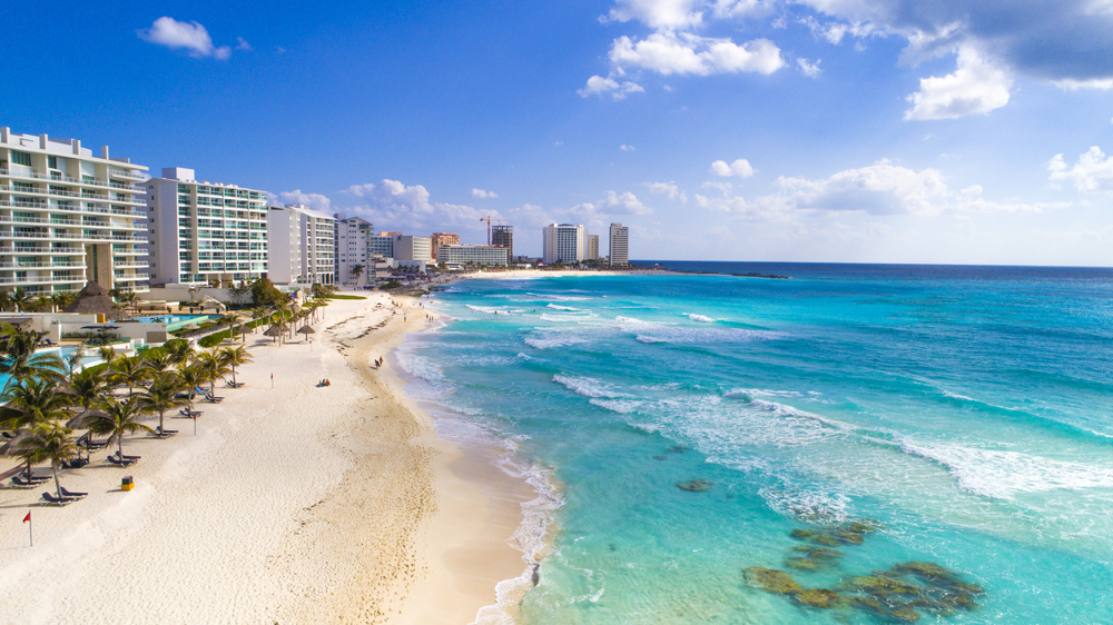 beach with buildings and clear blue water cancun travel tips