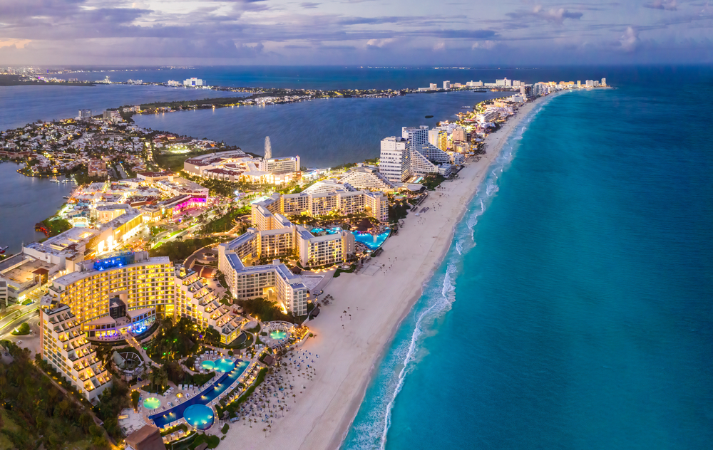 aerial view of a beach with lots of hotels and beaches lit up in the evening cancun travel tips