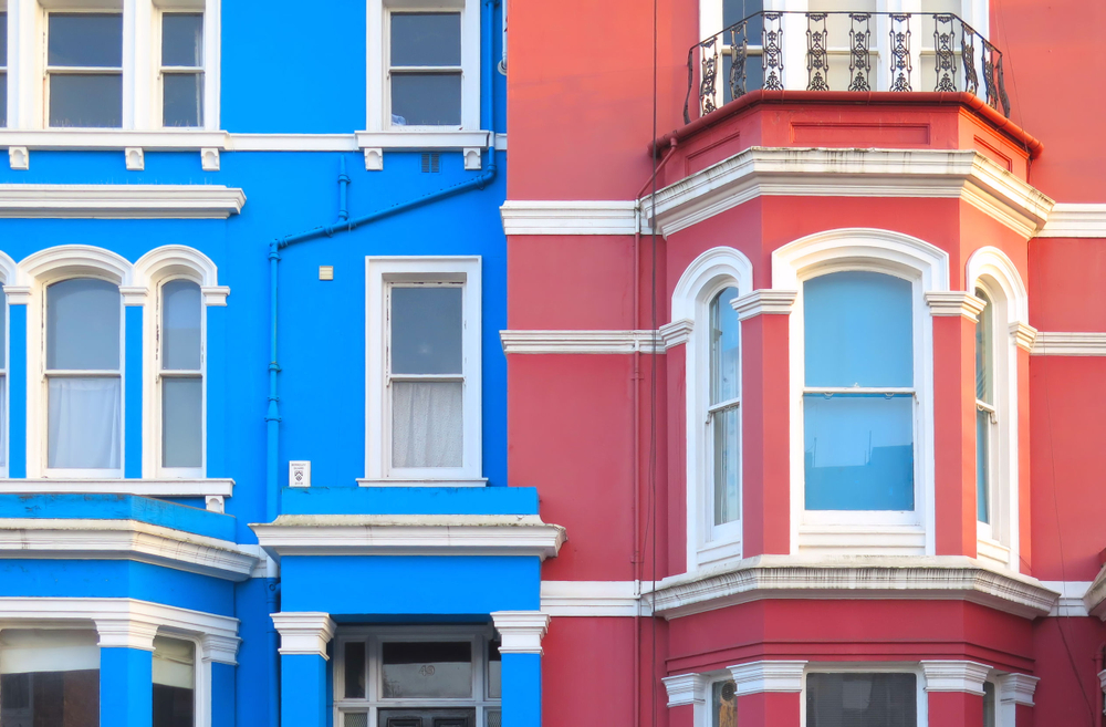 Colorful houses in Notting Hill. One is pink and one is blue. The article is about the most beautiful places in London.