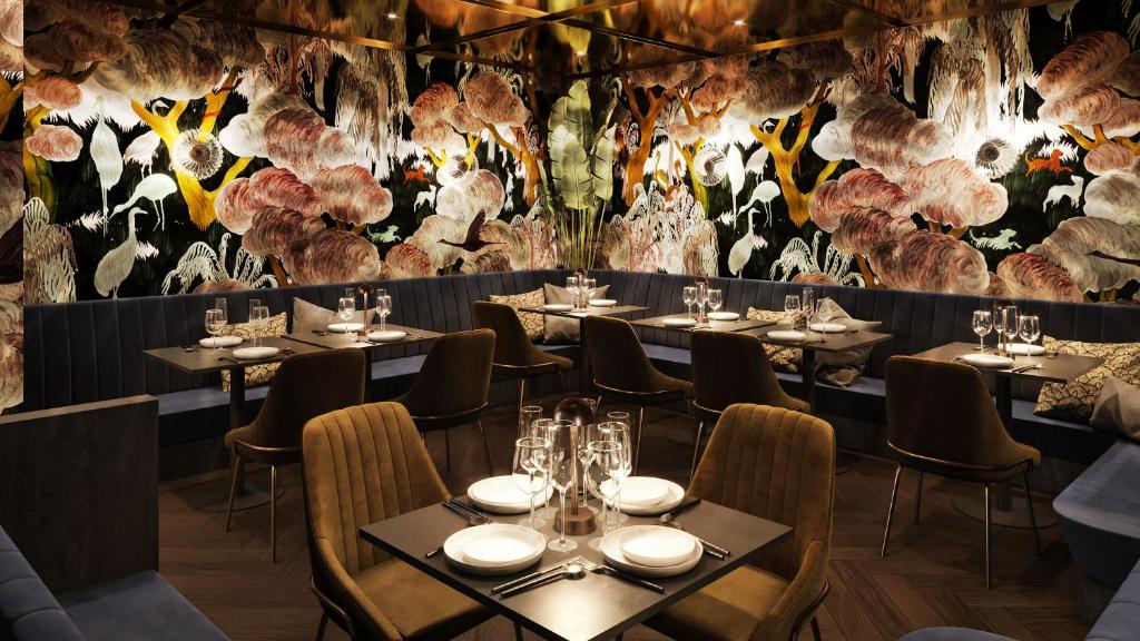 Eccentric dining room decorated with bird wallpaper and velvet chairs. The article is about boutique hotels in London