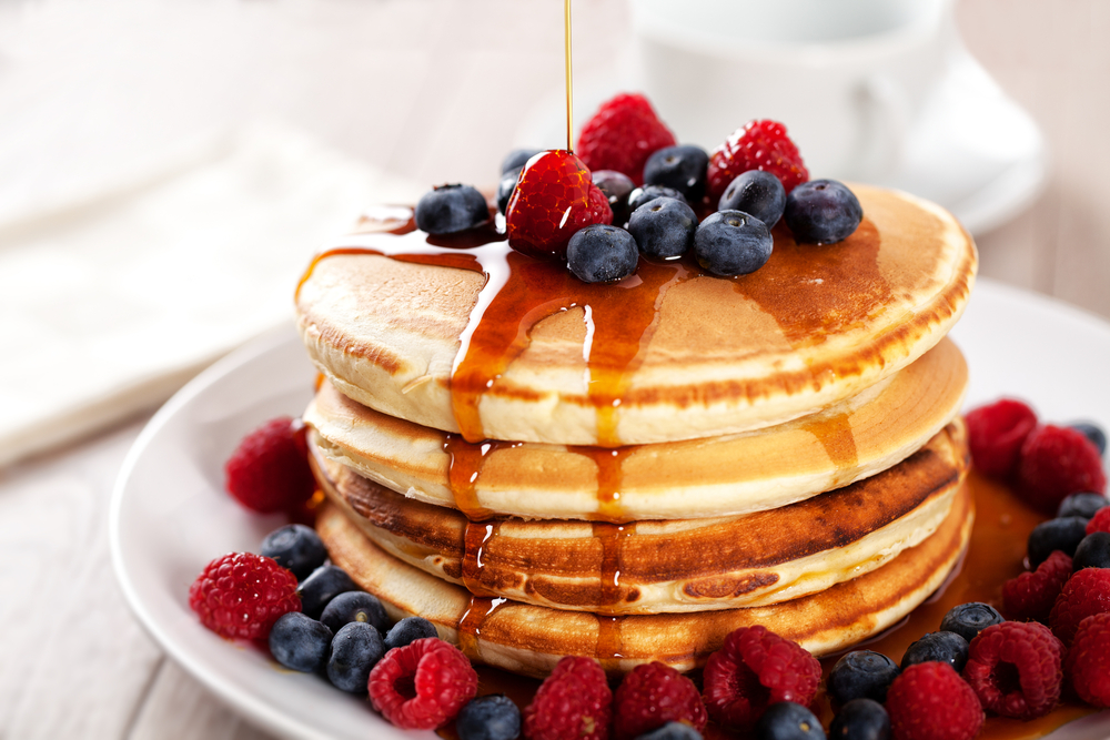 A slack of pancakes with fruits on top and at the bottom with syrup poured on.  The article is about the breakfast in Dublin. 