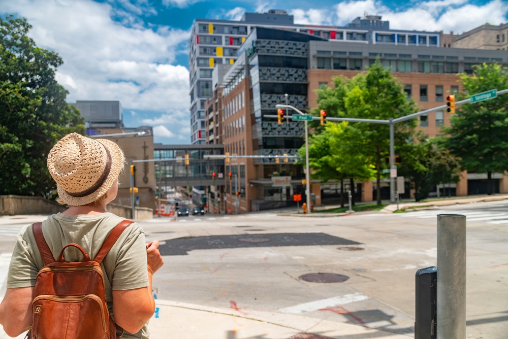 woman wearing a backpack and a hat admiring the buildings traveling to baltimore