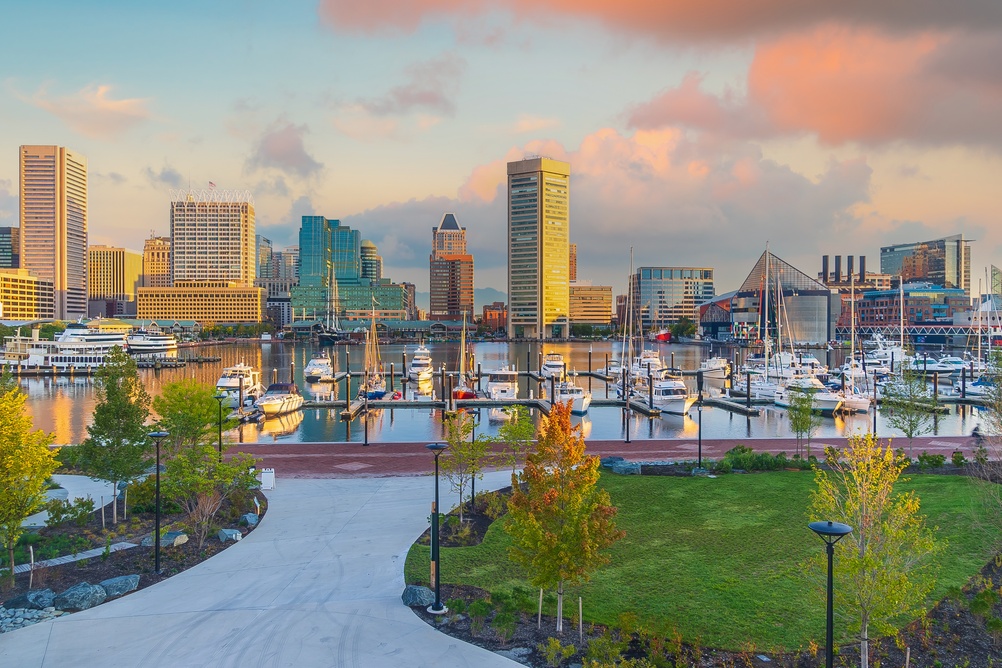 walking path to a harbour with lots of boats in the water and skyscrapers in the backdrop baltimore inner harbour