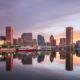 buildings reflecting in the water during sunset traveling to Baltimore