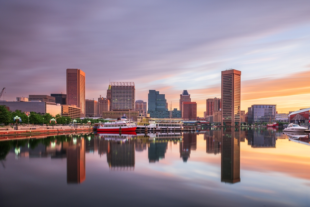 buildings reflecting in the water during sunset traveling to Baltimore